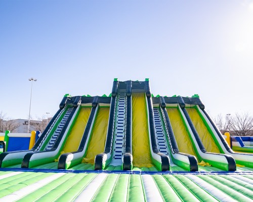 A large inflatable water slide with multiple lanes, set against a clear blue sky.