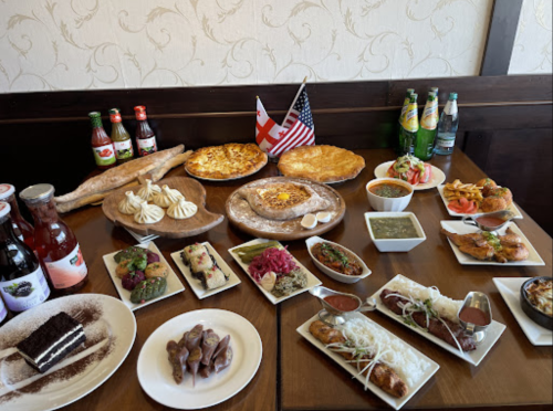 A table filled with various dishes, drinks, and desserts, featuring Georgian and American flags.