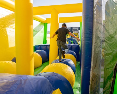 A person navigates an inflatable obstacle course, balancing on large colorful balls.