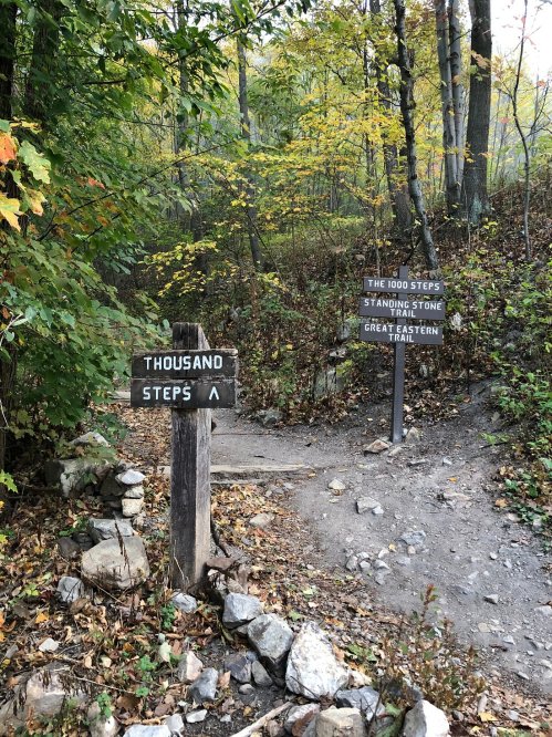 A trail sign indicating "The 1000 Steps" and "Standing Stone" on the Great Eastern Trail, surrounded by autumn foliage.