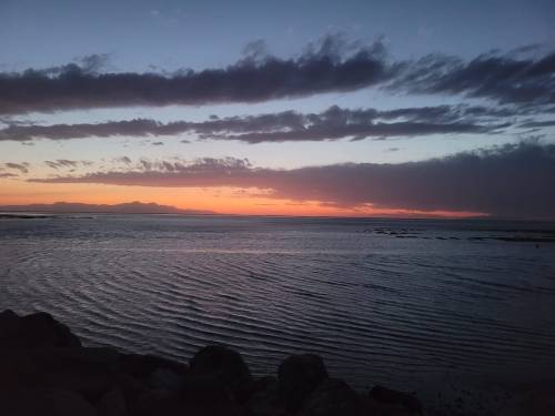 A serene sunset over calm waters, with colorful clouds reflecting on the horizon.