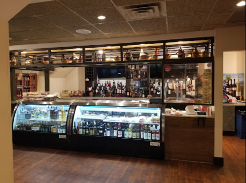A well-stocked bar with various bottles of wine and spirits displayed behind a glass counter in a cozy setting.