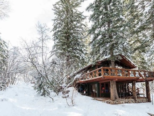 A cozy cabin surrounded by snow-covered trees, nestled in a winter landscape.