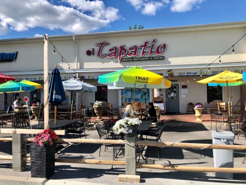 Outdoor seating area of Tapatio Mexican Restaurant, featuring colorful umbrellas and potted plants.