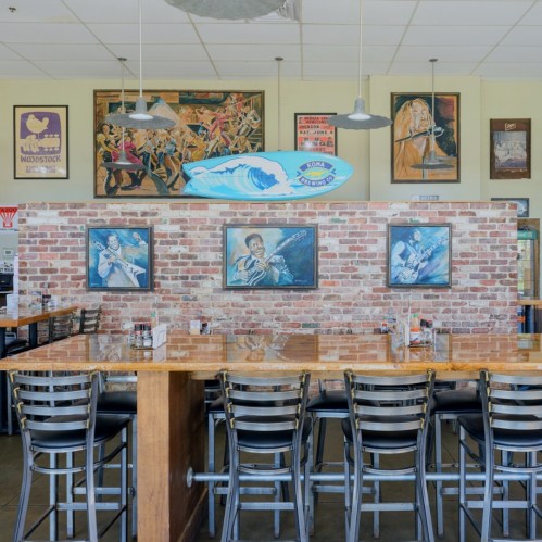 A vibrant restaurant interior with brick walls, wooden tables, and music-themed artwork.