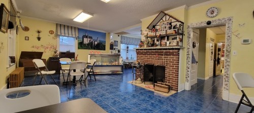 Cozy interior of a room with blue tile flooring, a fireplace, and seating areas, decorated with various knick-knacks.