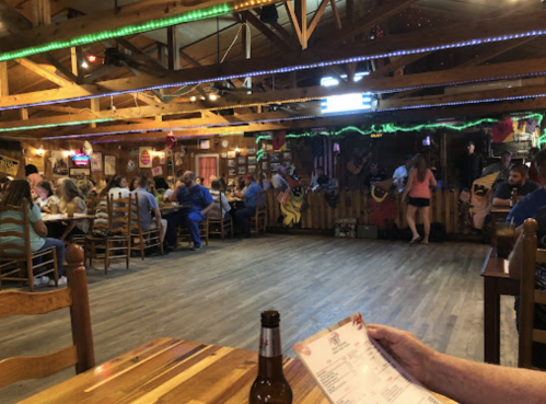 A lively restaurant interior with diners, a band performing, and colorful decorations under wooden beams.