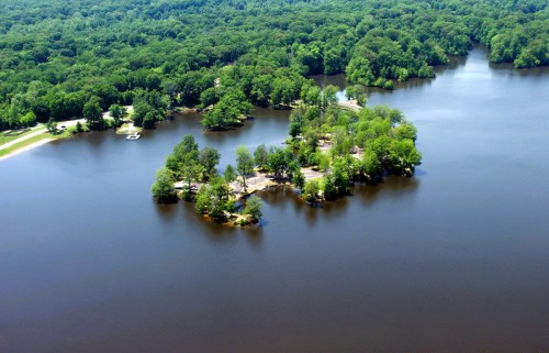 Aerial view of a serene lake surrounded by lush green trees and small islands.