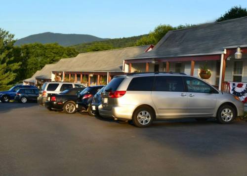 A row of parked cars in front of a motel, with mountains in the background and a clear blue sky.