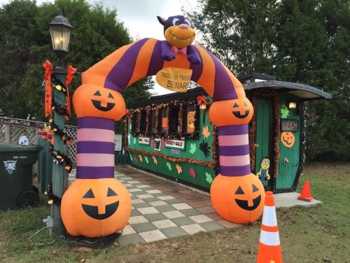 A colorful inflatable arch with pumpkins and a bat welcomes visitors to a Halloween-themed booth.