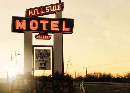 A vintage motel sign at sunset, featuring "MOTEL" and "VACANCY" with amenities listed below.