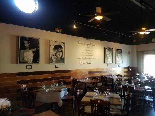 Interior of a restaurant featuring wooden tables, chairs, and black-and-white portraits on the wall.