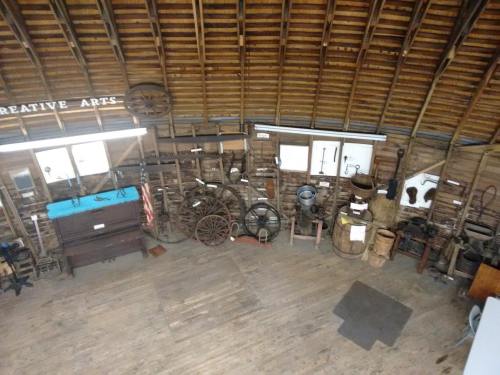 Interior of a rustic space showcasing various vintage tools and equipment, with wooden beams and a wooden floor.