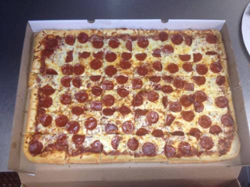 A large rectangular pizza topped with pepperoni slices, placed in a pizza box.