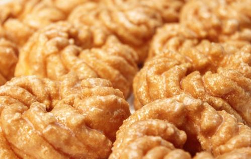 Close-up of golden, spiral-shaped pastries dusted with sugar, arranged closely together.