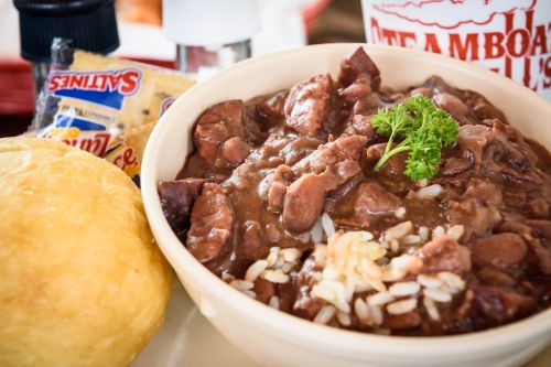 A bowl of hearty beans and rice topped with parsley, accompanied by a cornbread muffin and condiments.