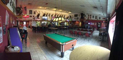 A spacious bar with a pool table, deer mounts on the walls, and empty tables and chairs in a relaxed atmosphere.