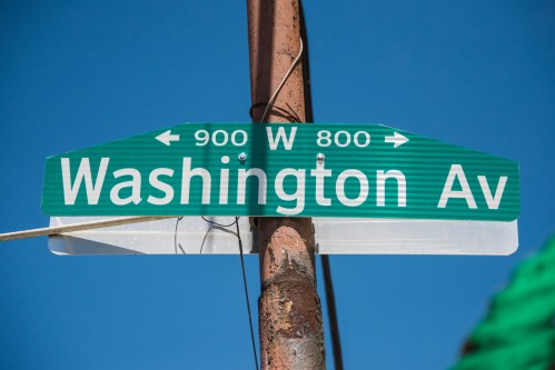 Green street sign for Washington Avenue with directional arrows, against a clear blue sky.