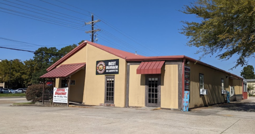 Exterior of a restaurant named "Best Burger" with a red roof and signage, set against a clear blue sky.