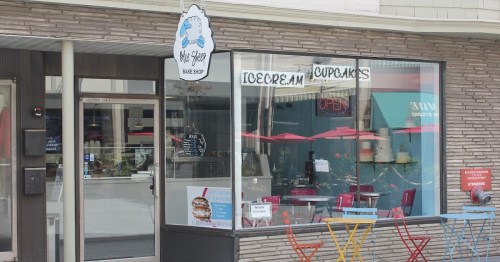 A colorful ice cream and cupcake shop with a welcoming "Open" sign and outdoor seating.