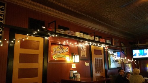 A cozy restaurant interior with warm lighting, featuring a train display along the wall and patrons enjoying their meals.