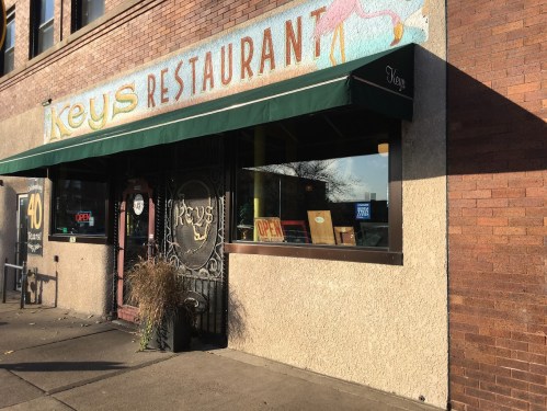 Exterior of Keys Restaurant with a colorful sign, green awning, and open sign in the window.