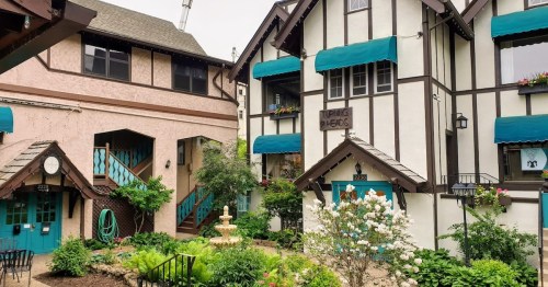 Charming courtyard with a fountain, surrounded by Tudor-style buildings and lush greenery.