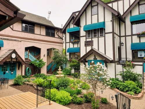 Charming courtyard with a fountain, surrounded by colorful buildings and lush greenery.
