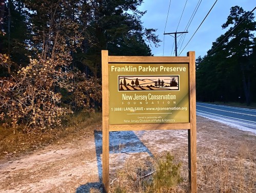 Sign for Franklin Parker Preserve, New Jersey Conservation Foundation, near a road with trees in the background.