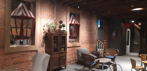 Cozy interior with brick walls, decorative windows, a wooden cabinet, and seating areas in a warm, inviting atmosphere.