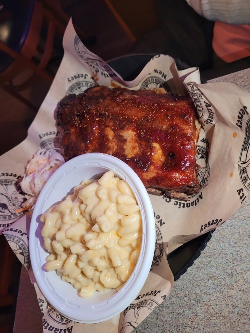 A plate of barbecue ribs with a side of creamy macaroni and cheese, served on parchment paper.