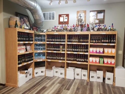 A wooden display with shelves filled with various bottles of wine and boxes, showcasing a variety of labels and colors.