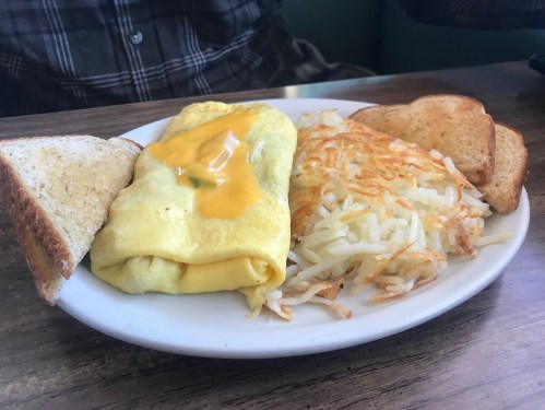 A plate with a cheese omelet, hash browns, and two slices of toasted bread.