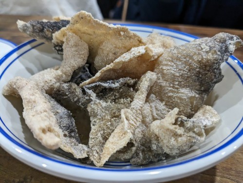 A bowl of crispy fish skin snacks, lightly seasoned and arranged in a casual presentation.