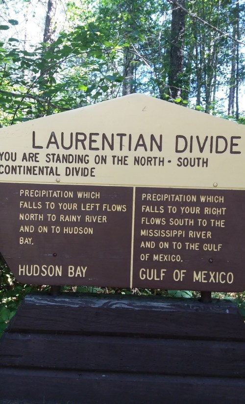 Sign marking the Laurentian Divide, indicating water flow directions to Hudson Bay and the Gulf of Mexico.
