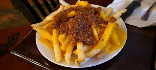 A plate of French fries topped with chili and melted cheese.