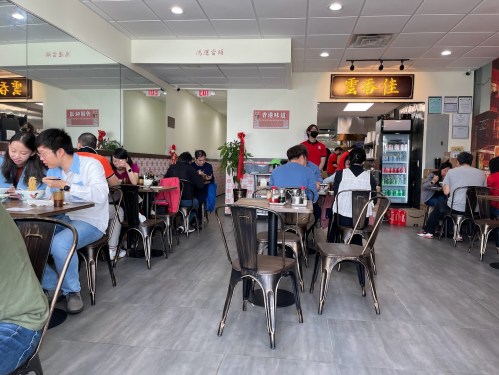 A busy restaurant interior with diners at tables, enjoying meals and chatting in a casual atmosphere.