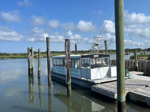 A boat named "Gulfstream" docked at a pier on a calm waterway under a blue sky with scattered clouds.