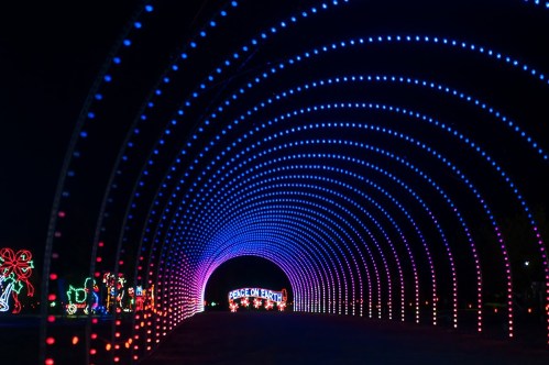 A colorful light tunnel with blue and purple lights, leading to a sign that reads "Peace on Earth."