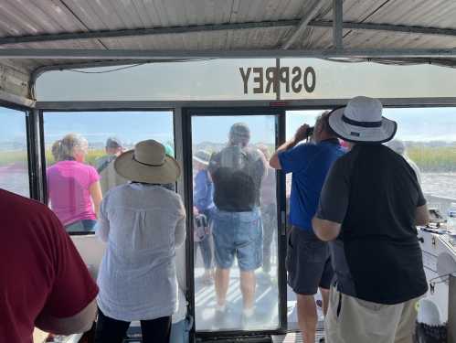 A group of people on a boat, looking out through a large window at a scenic view.