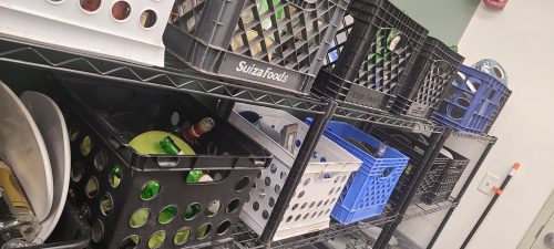 Shelves with various plastic storage crates in black and blue, containing assorted items.