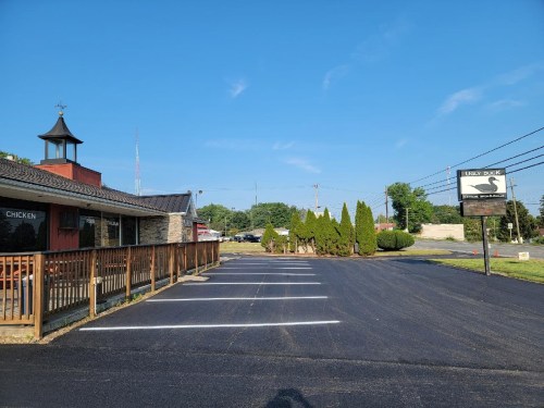 A restaurant with a sign reading "Hickory Dick" and a clear blue sky, featuring a parking lot and greenery.