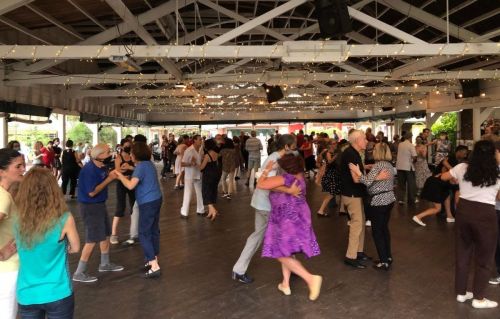 A lively dance floor filled with people dancing and enjoying a social event under string lights.