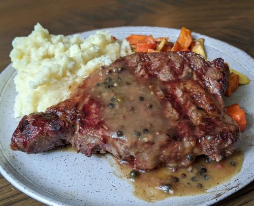 A plate featuring a juicy steak with pepper sauce, mashed potatoes, and roasted vegetables.