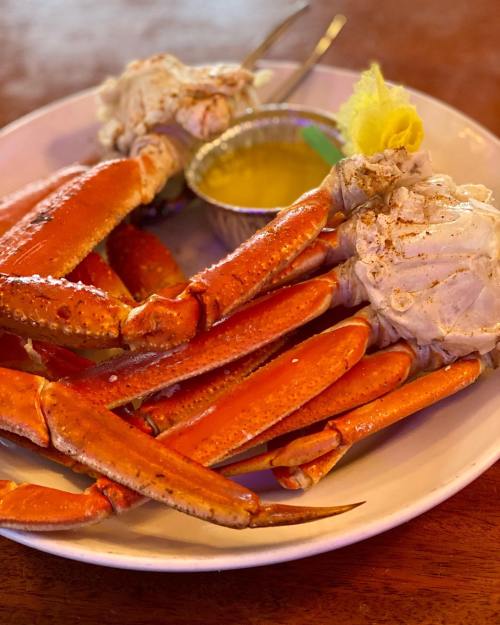 A plate of cooked crabs with a small bowl of melted butter for dipping.