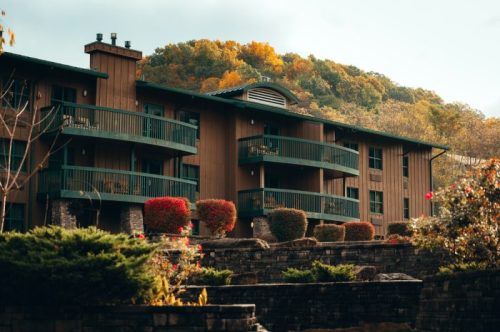 A wooden building with balconies surrounded by colorful autumn foliage and landscaped gardens.