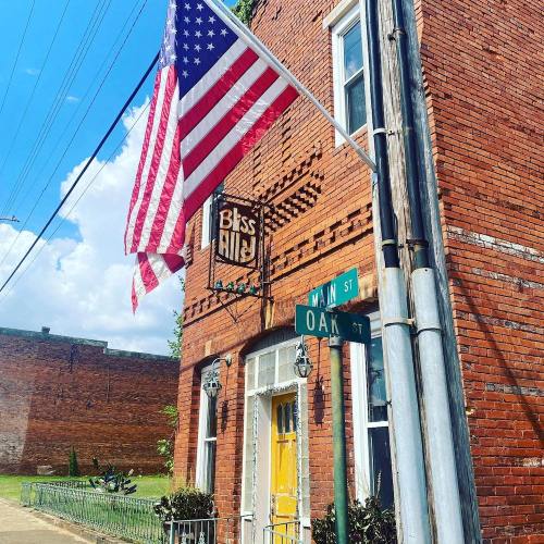 A brick building with a yellow door, an American flag, and street signs for Main St and Oak St.