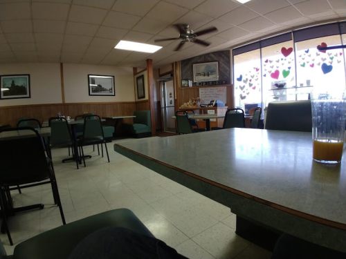 A quiet diner interior with empty tables, chairs, and a window decorated with heart-shaped cutouts.