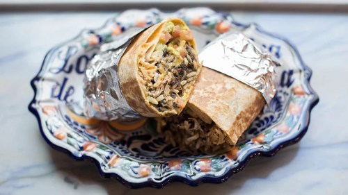 A colorful plate holds a wrapped burrito and a partially unwrapped burrito filled with rice and meat.
