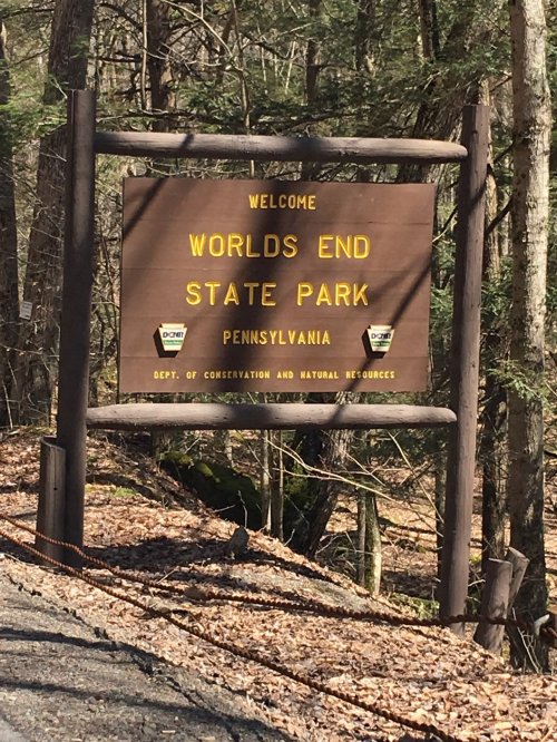 Welcome sign for Worlds End State Park in Pennsylvania, surrounded by trees and natural scenery.